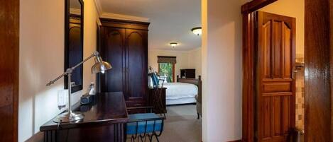 A hotel room with a desk, chair, bed, and a wooden door.