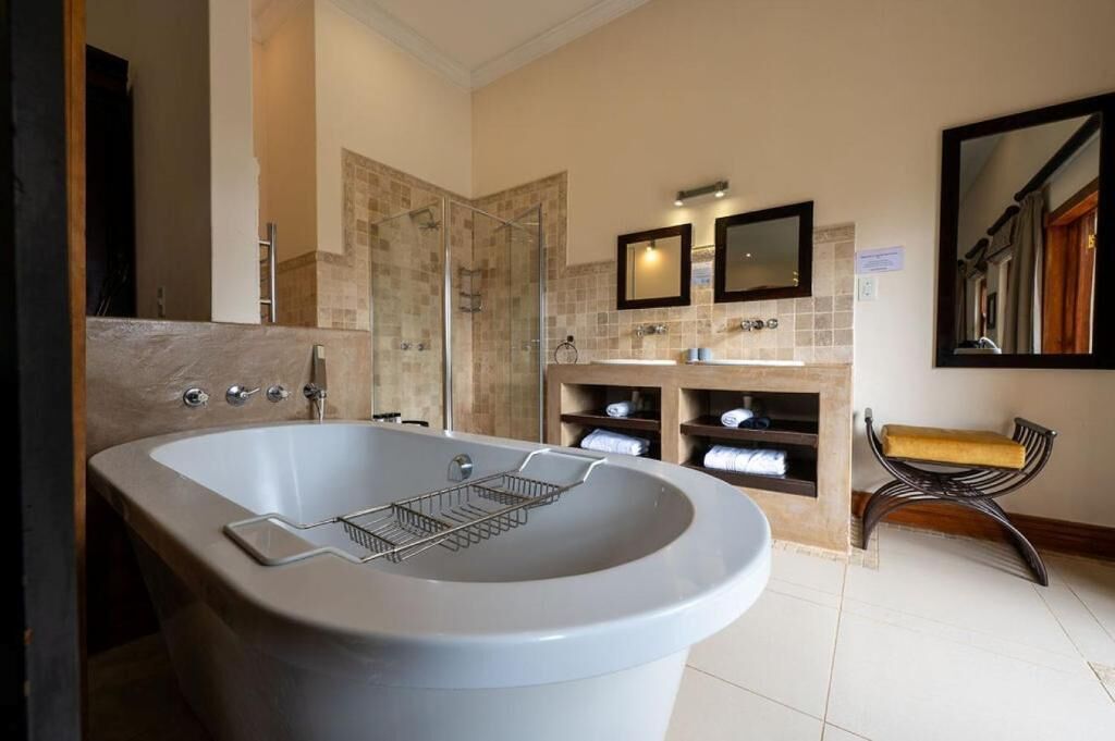 A bathroom with a freestanding bathtub, a shower enclosure, a vanity with a mirror, and a towel rack.