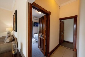 A hotel hallway with a bed, a TV, and a lamp. - IL Castello Boutique Hotel (Clarens)