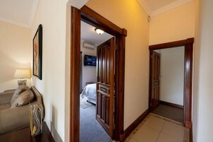 Un pasillo de hotel con una cama, un televisor y una lámpara.