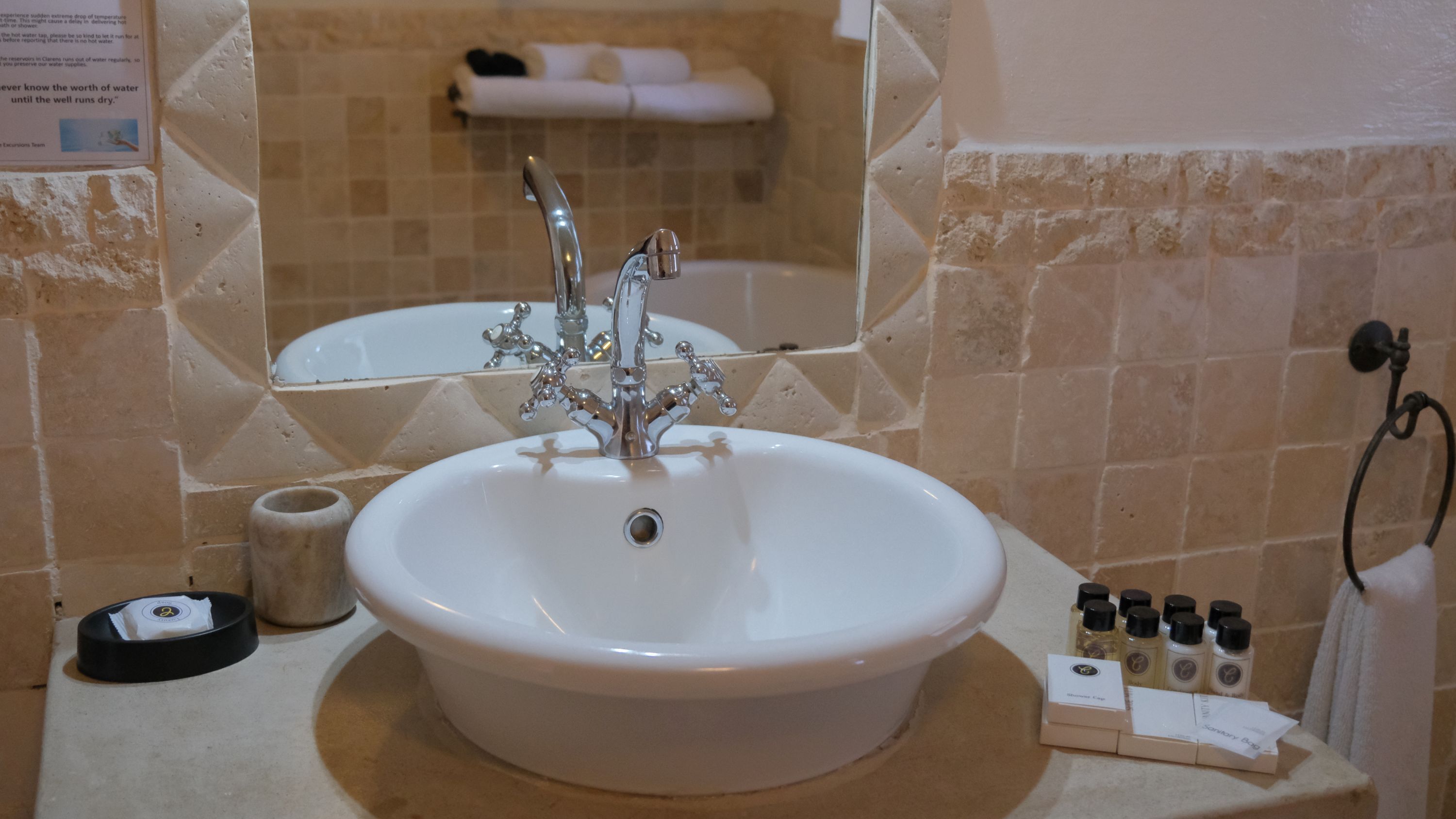 A bathroom with a white sink, a mirror, and a towel rack.