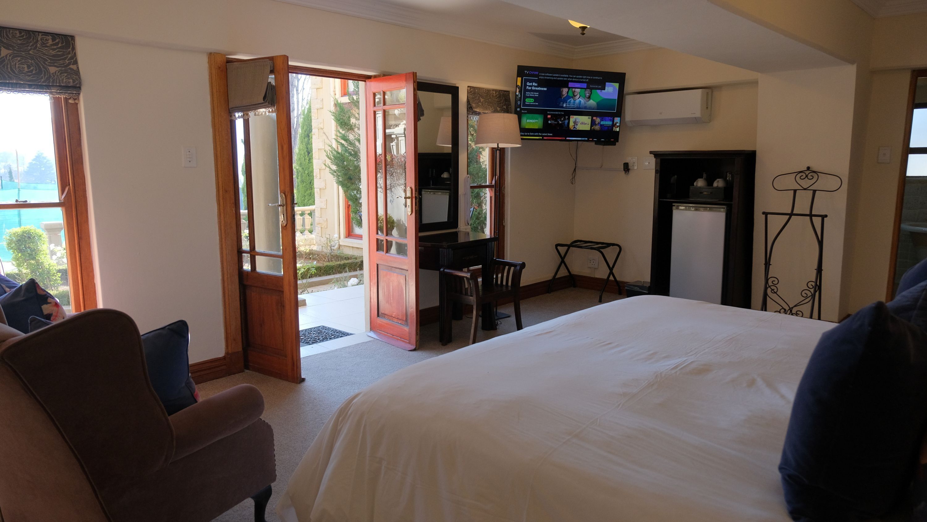 A hotel room with a bed, a desk, a TV, and a view of the outdoors.