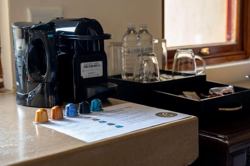 Une machine à café, des bouteilles d  ’eau et un plateau contenant une dosette de café et un mode d’emploi, le tout posé sur un plan de travail.