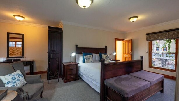 A bedroom with a bed, a sofa, a nightstand, a dresser, and a window with a view.