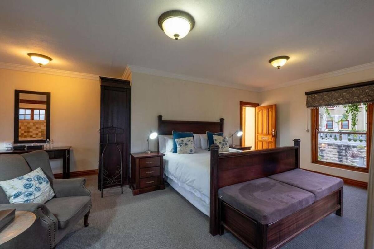 A bedroom with a bed, a sofa, a nightstand, a dresser, and a window with a view.