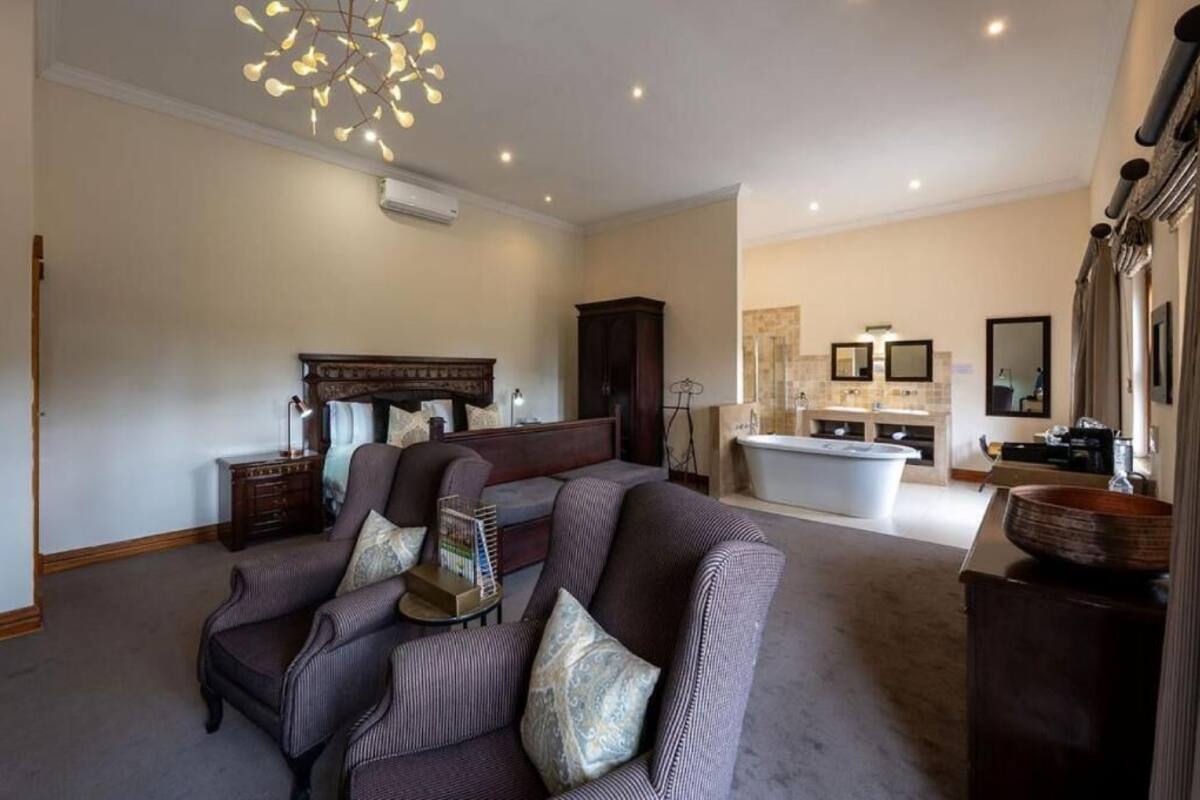 A living room with a sofa set, a fireplace, a large mirror, and a bathroom with a bathtub and vanity.