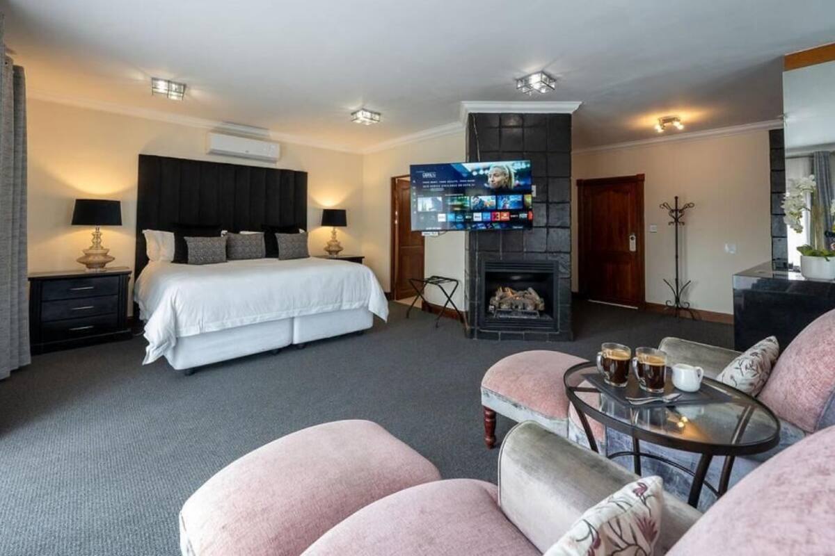 A hotel room with a bed, a TV, a fireplace, and a seating area with a table.