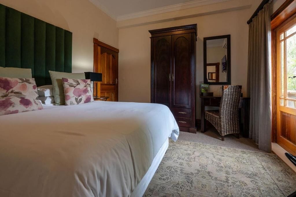 A bedroom with a large bed, a wardrobe, a chair, and a mirror.