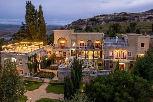 A large, multi-story building with a courtyard, multiple balconies, and a view of the surrounding landscape.