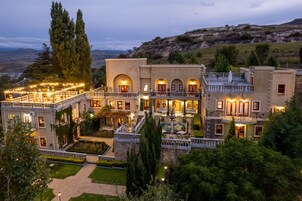 Un edificio grande de varios pisos con un patio interior, múltiples balcones y vistas del paisaje circundante.