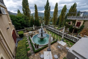 A courtyard with a fountain, outdoor seating, and tall trees.