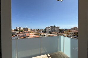 Un balcon offrant une vue dégagée sur le paysage urbain côtier, avec ses bâtiments et une ligne de côte lointaine.