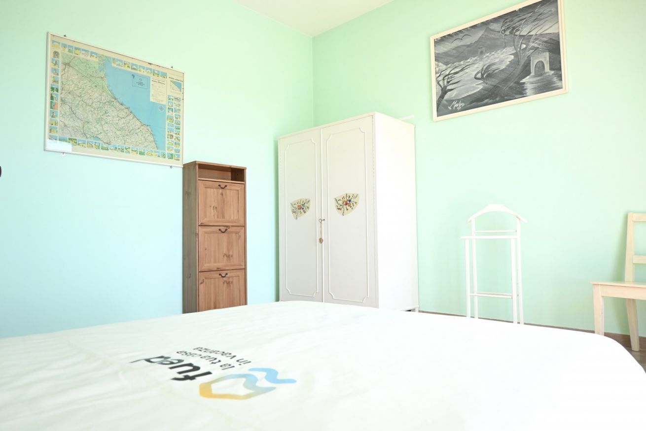 Een slaapkamer met een bed, een kaart aan de muur, een kledingkast en een lijst met een foto.