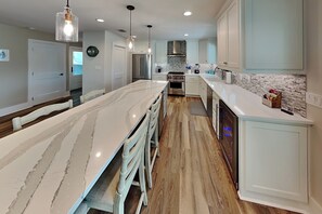 A modern kitchen with a marble countertop, stainless steel appliances, and light wood flooring. - The Salty Flamingo (Rockport)