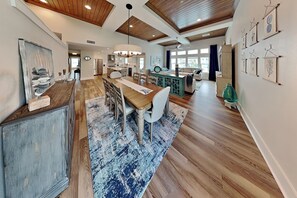 A spacious kitchen with wooden cabinets, a dining area with a large table, and a living area with a sofa and a coffee table. - The Salty Flamingo (Rockport)