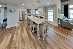 A modern kitchen with a central island, stainless steel appliances, and pendant lighting. - The Salty Flamingo (Rockport)