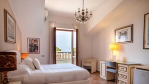 Un dormitorio con cama, escritorio, silla y balcón con vistas.
