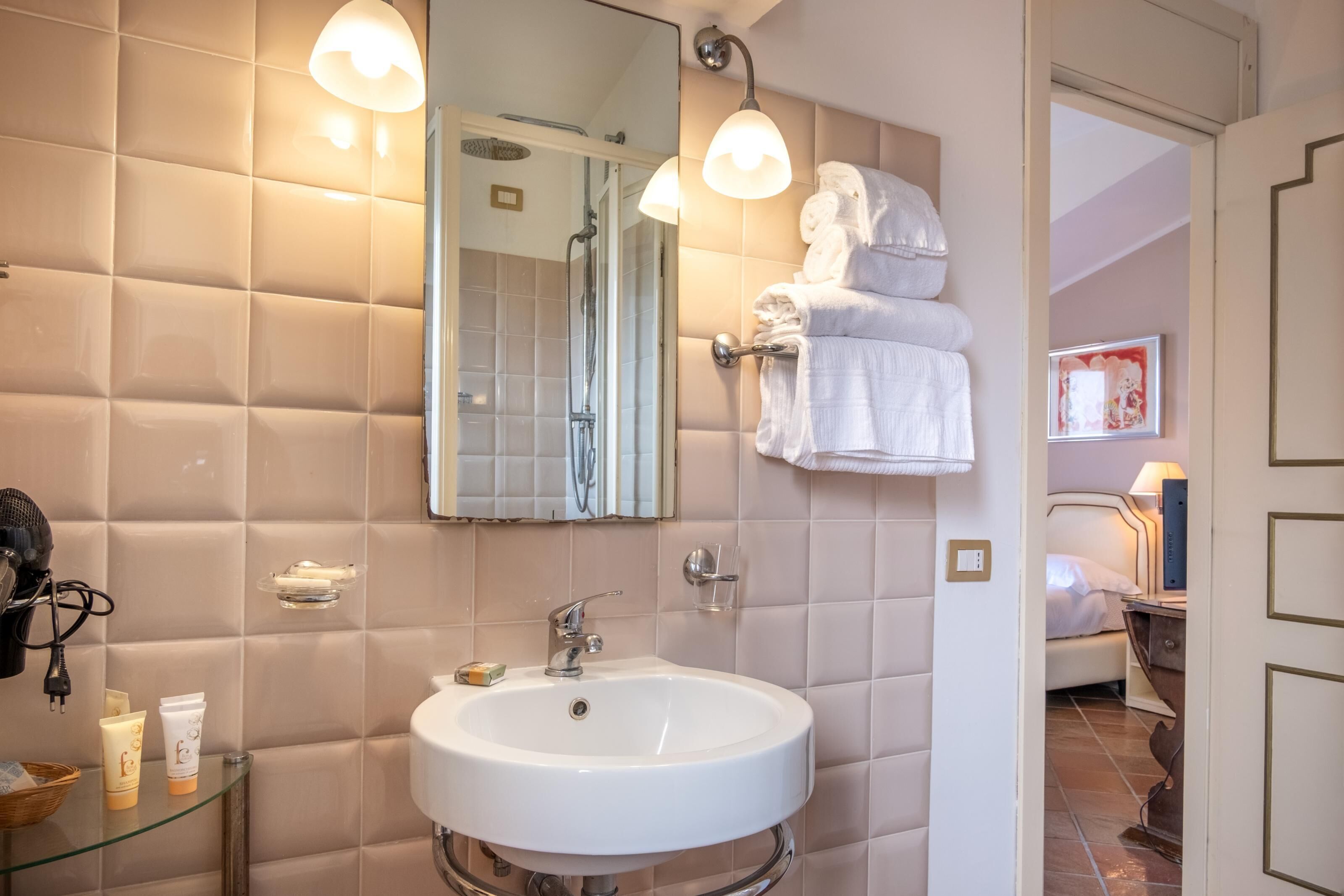 A bathroom with a large mirror, a sink, and a towel rack.