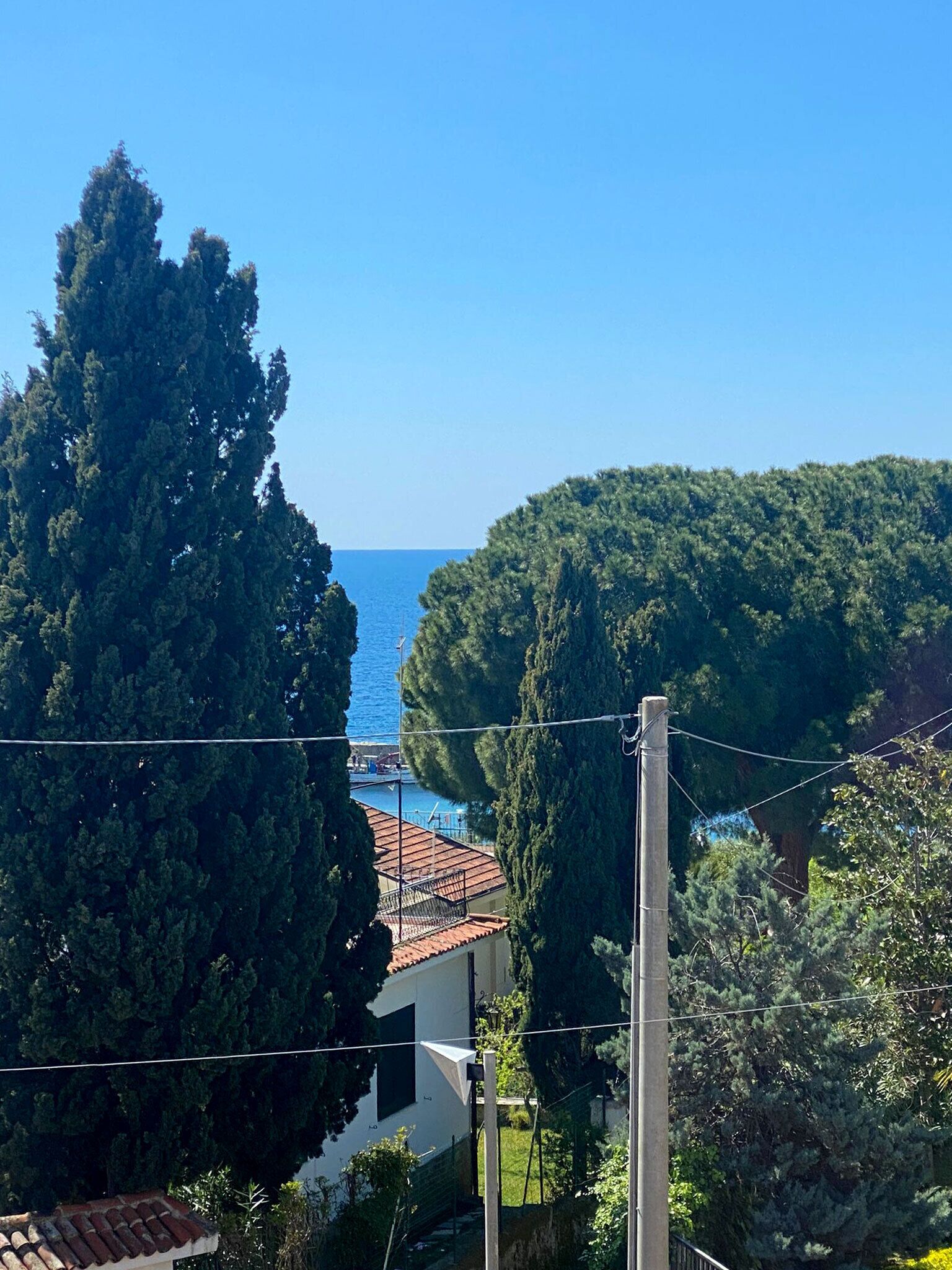 Μια παραθαλάσσια θέα με ένα σπίτι, δέντρα και έναν καθαρό ουρανό.