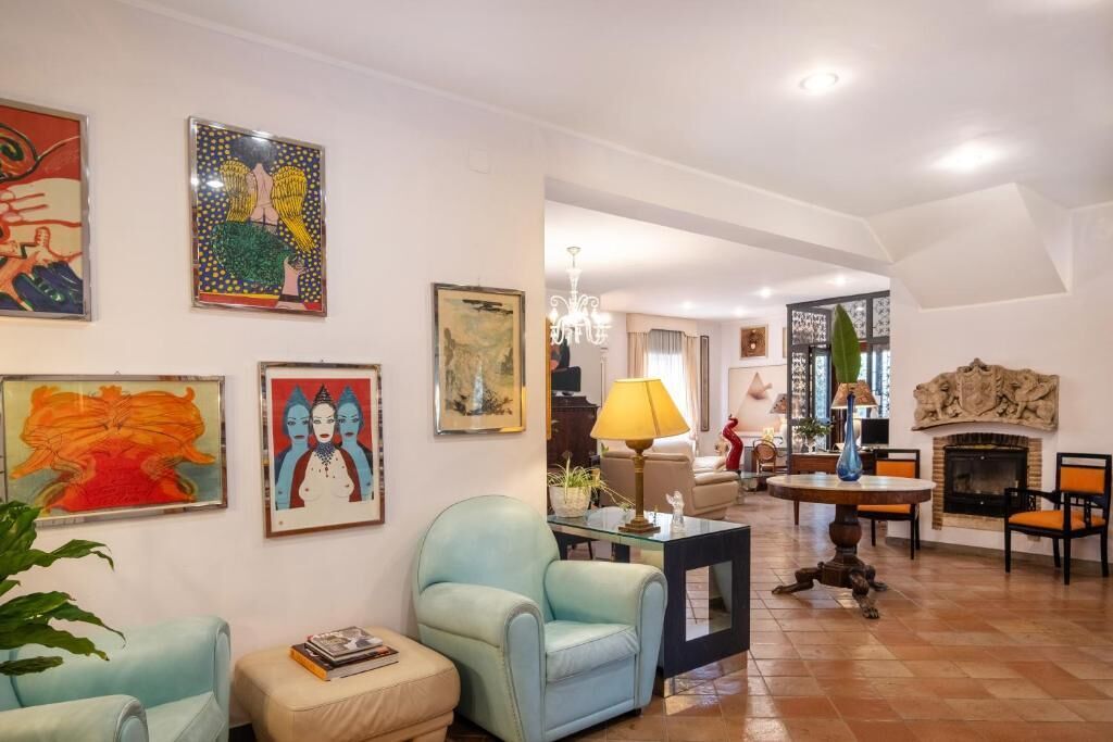 Un salón amplio con chimenea, una araña y obras de arte en las paredes.