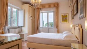 Un dormitorio con cama, cómoda, lámpara de araña y ventana con cortinas.