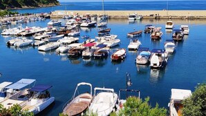 Un puerto deportivo con numerosas embarcaciones amarradas, una playa de arena y un cielo azul despejado.