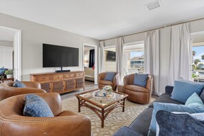 A spacious living room with leather sofas, a glass coffee table, and a flat-screen TV. - Salty Sandpiper (Rockport)