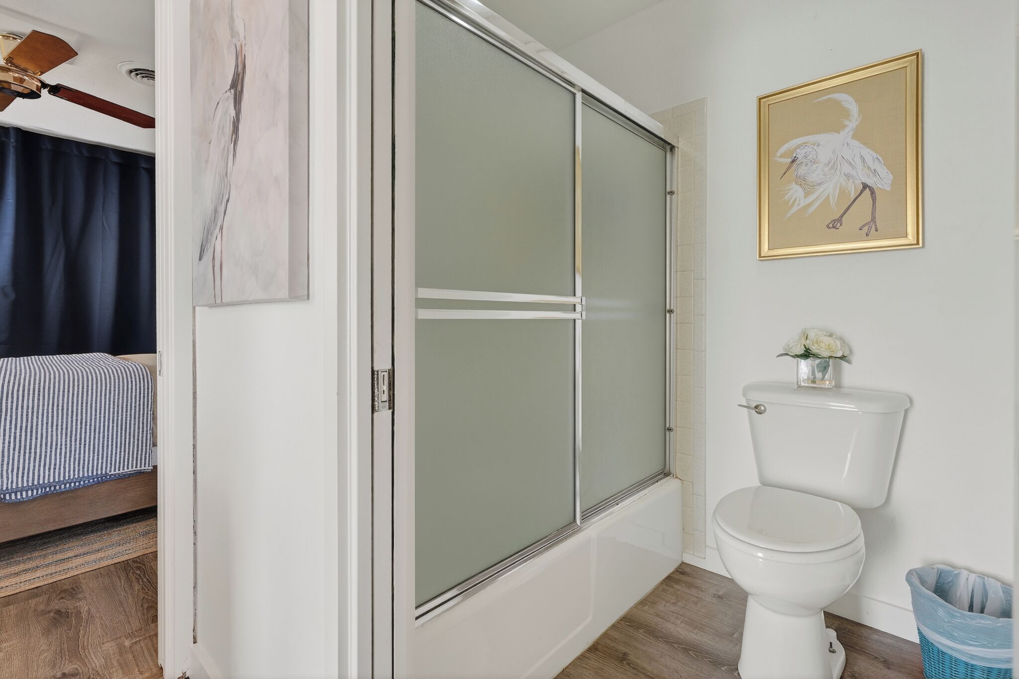 Un bagno con il water, uno spazio doccia e un letto nella stanza adiacente.