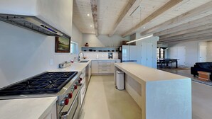 A modern kitchen with a central island, built-in appliances, and a dining area with a table and chairs.