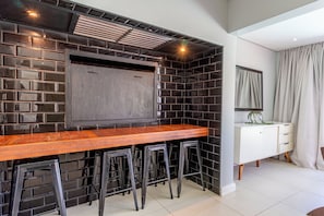 A kitchen with a wooden bar, black tiled backsplash, and a white cabinet.