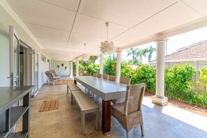 An outdoor dining area with a long table, benches, and wicker chairs.
