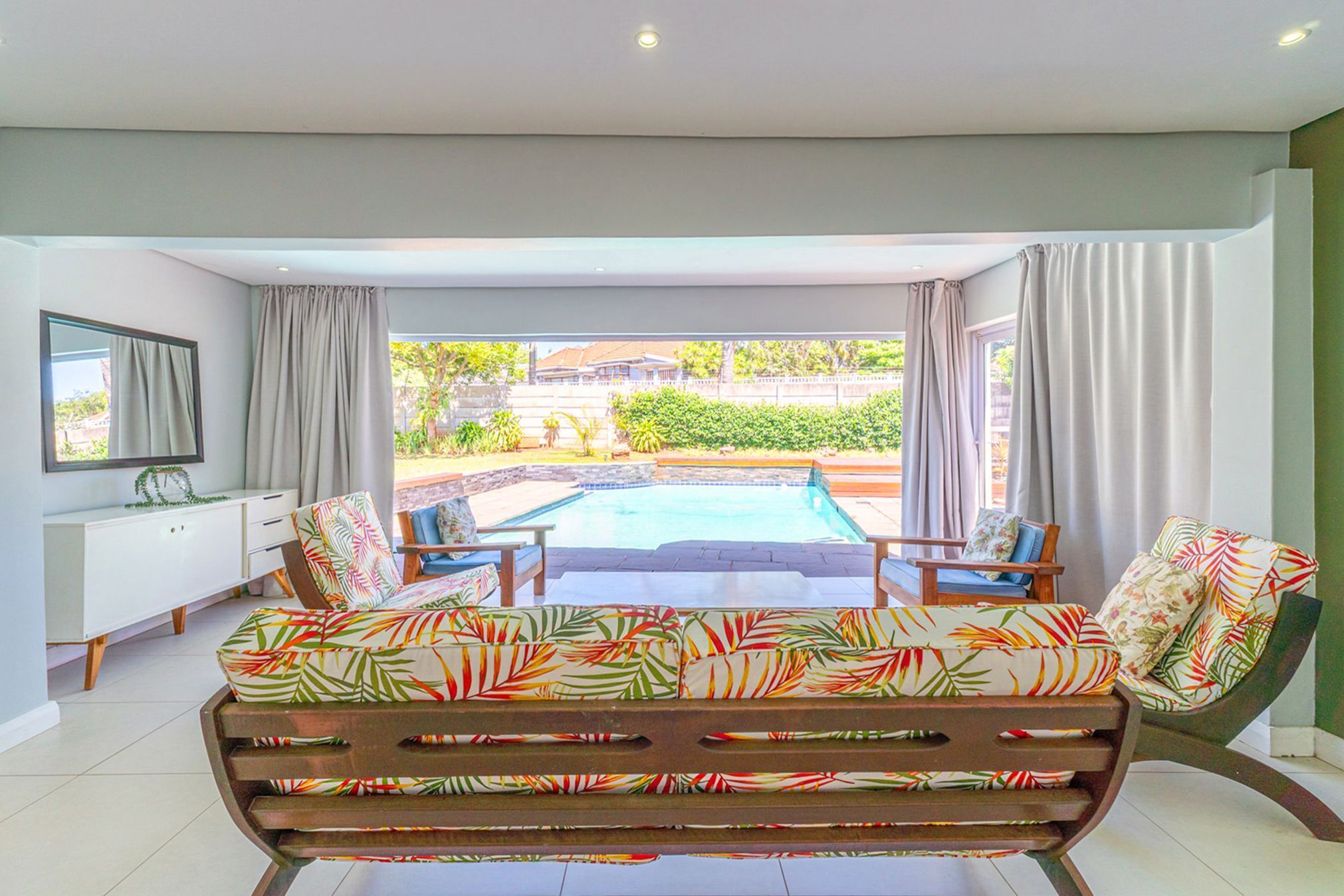 A modern living room with a pool view, a sofa, and a TV.