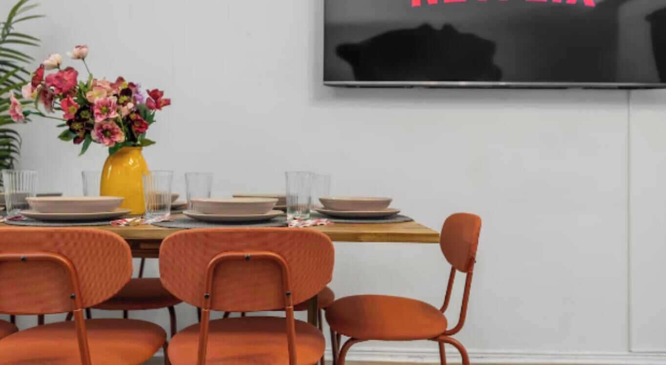 Et spisebord dækket med tallerkener, glas og en gul vase med blomster.