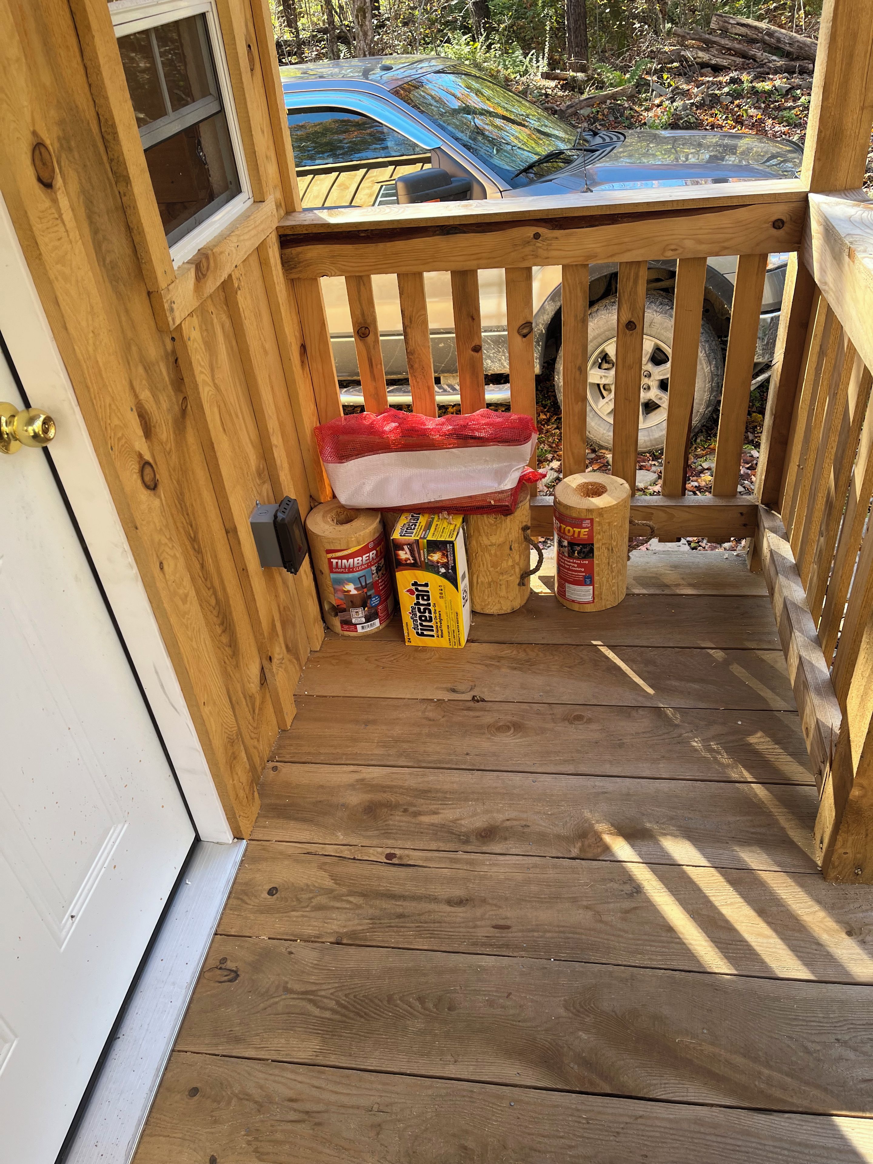 A wooden deck with a railing, a car parked outside, and fire safety equipment.
