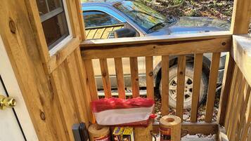 A wooden deck with a railing, a car parked outside, and fire safety equipment.
