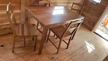 A wooden dining table with four chairs in a room with wooden walls and floors.