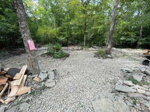 A forested area with a gravel path, wooden planks, and a wheelbarrow.