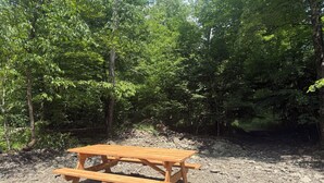 Ein Holztisch für ein Picknick in bewaldeter Landschaft mit erdigem Untergrund.