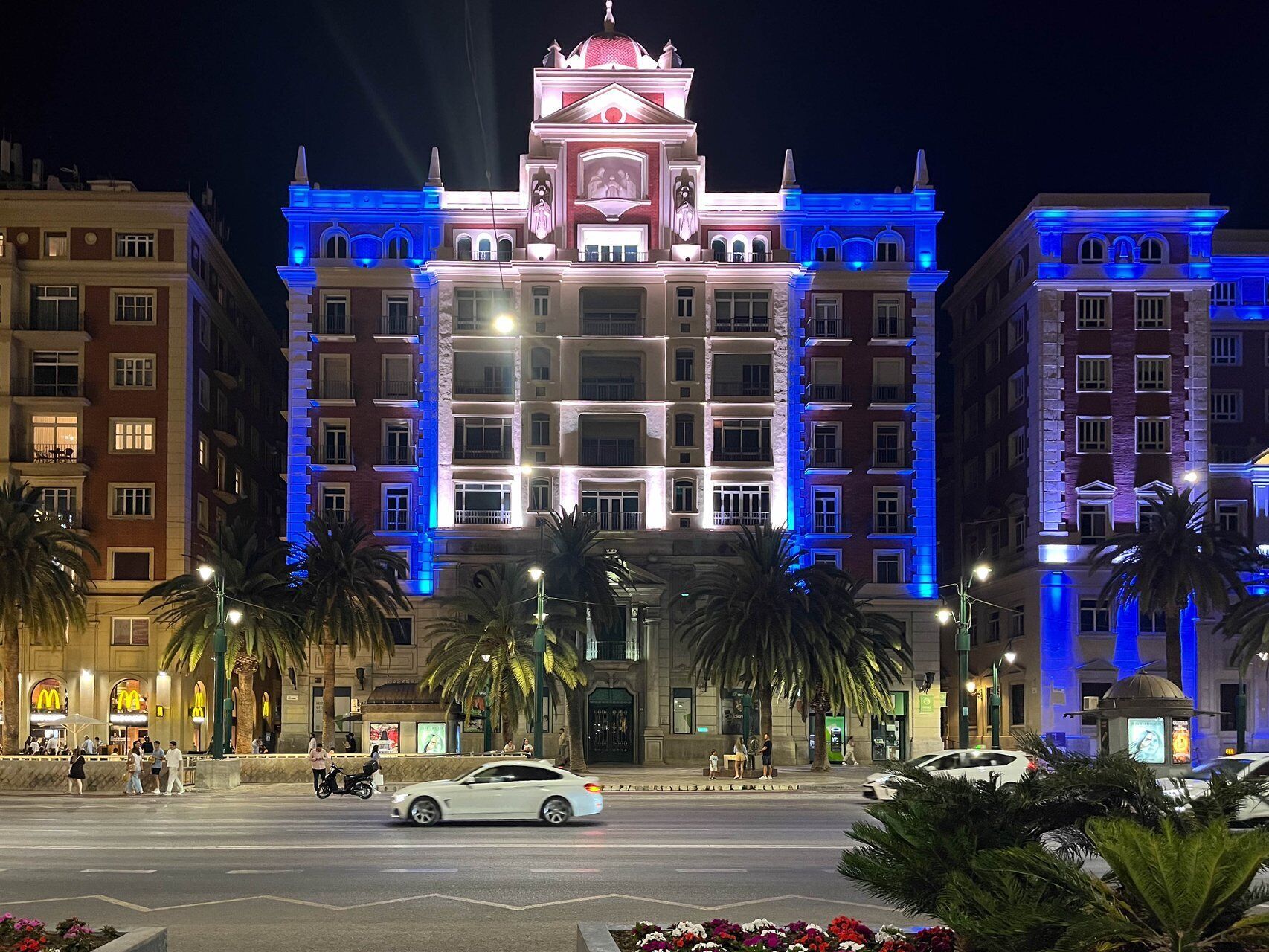Un hotel de varios pisos con una destacada torre de reloj, grandes ventanales y una fachada bien iluminada.