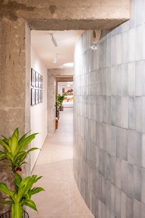 A hallway with tiled walls, framed pictures, and potted plants. - GuestReady - Stylish art and comfort Malaga centre (Málaga)