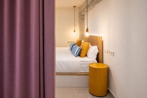 Ein Schlafzimmer mit einem Bett, Kissen, einer Nachttischlampe und einem Mülleimer.