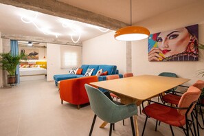 A modern living room with a sofa, chairs, a dining table, and a painting on the wall. - GuestReady - Stylish art and comfort Malaga centre (Málaga)