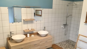 A modern bathroom with two sinks, a shower, and a mirror.