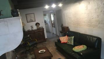 Ein gemütliches Wohnzimmer mit einem grünen Sofa, einem Holzschrank und einem Esstisch.