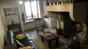 A living room with a fireplace, a sofa, a table, and a chair.