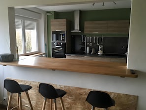 Eine moderne Küche mit Holzarbeitsplatte, integrierten Geräten und einer Bar mit Hockern.