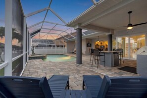 A pool area with lounge chairs, a bar, and a covered patio.