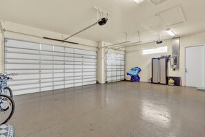 Eine geräumige Garage mit einem Fahrrad, einem blauen Stauraum und einem Kühlschrank.