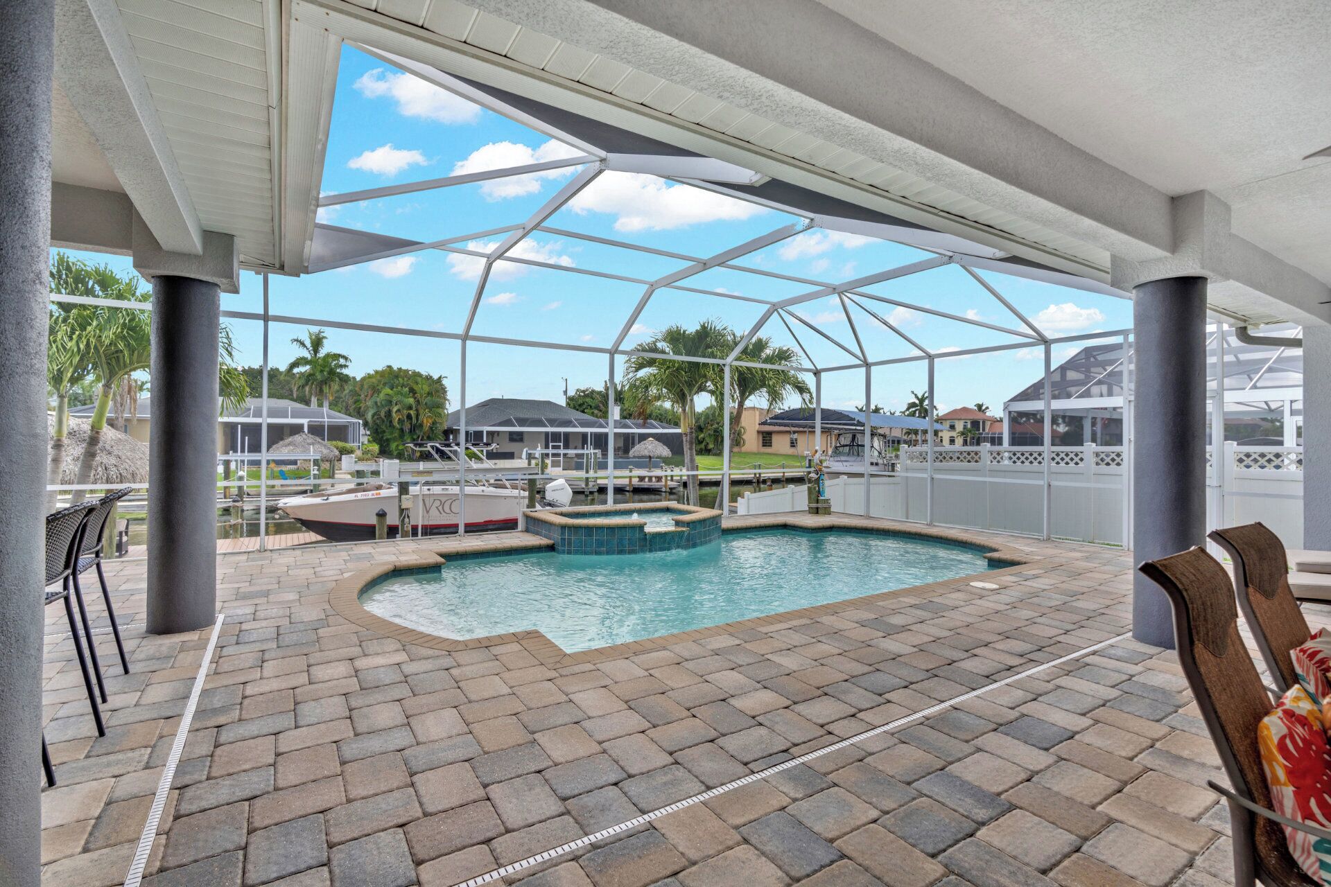 A covered swimming pool area with a view of the surrounding neighborhood, including houses and palm trees.