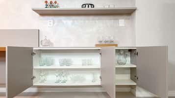 A kitchen with open cabinets displaying glassware and a shelf with decorative items.